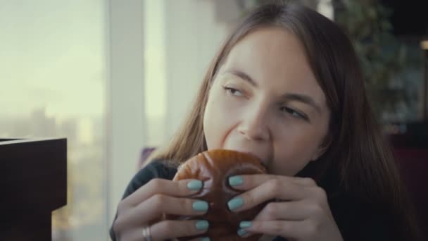 Görüntüleri genç kadın fast food restoranında lezzetli hamburger yemek. - Video, Çekim