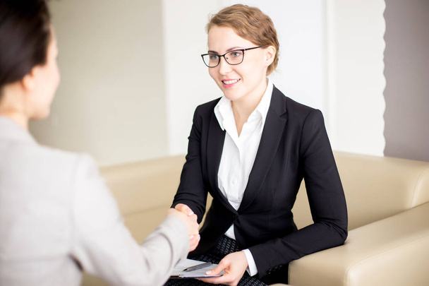 Portrait shot of attractive young manager wearing eyeglasses shaking hand of business partner after completion of productive project discussion - Photo, Image