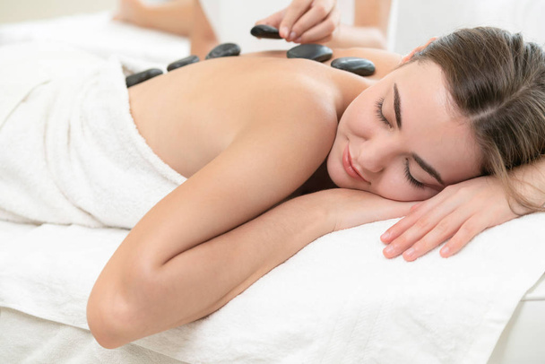 Frau bekommt Hot Stone Massage Behandlung durch professionelle Kosmetikerin Therapeutin im Wellness-Salon. Luxuriöses Wellness-, Rückenstress- und Verjüngungskonzept. - Foto, Bild