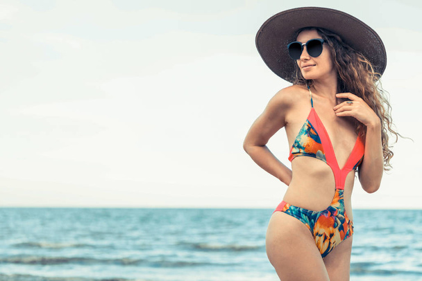 Onnellinen nuori nainen uimapuvussa, jolla on hyvä aika trooppisella rannalla kesällä lomamatkaa varten
. - Valokuva, kuva