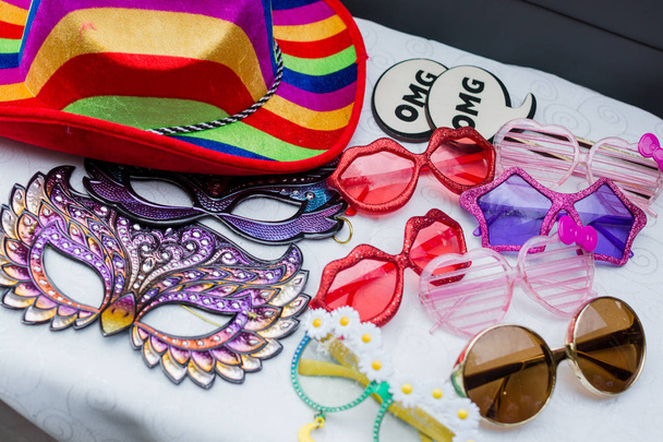 Foto adereços cabine, incluindo óculos engraçados, máscaras, sinais e chapéus coloridos
. - Foto, Imagem