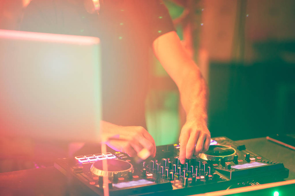 Dj mixes the track in the nightclub at party. DJ hands in motion - Foto, imagen