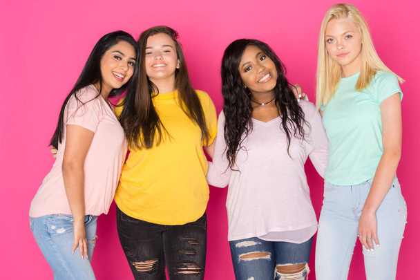 Group of four teen girls having fun together on a pink background - Foto, Imagen