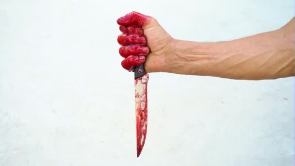 Hand and knife in the blood on a white background, male hand with a bloody knife - Footage, Video