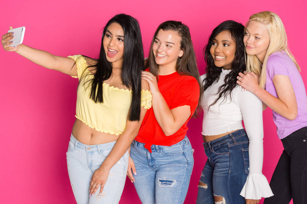 Group of four teen girls having fun together on a pink background - Φωτογραφία, εικόνα