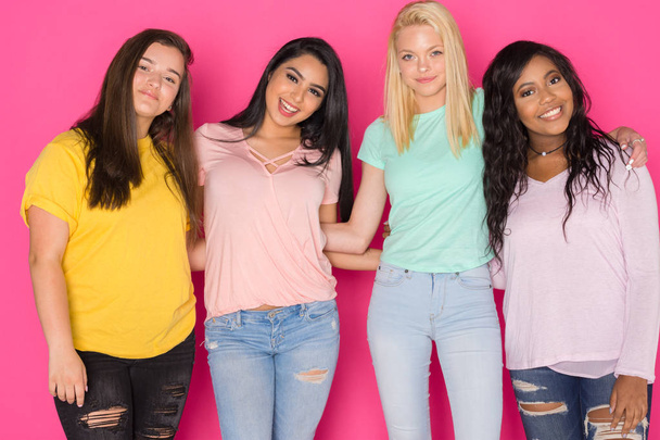 Group of four teen girls having fun together on a pink background - Photo, Image