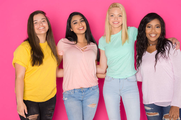 Groep van vier tiener meisjes plezier samen op een roze achtergrond - Foto, afbeelding
