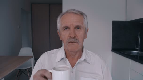 Portrait of Senior man with mustache drinking coffee at home in the kitchen in the morning - 映像、動画