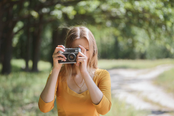 Beautiful girl in a yellow dress with camera - Foto, Imagem