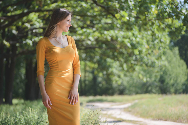 Woman in yellow dress posing on natural background - Fotoğraf, Görsel
