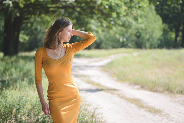 Beautiful Girl in a Yellow Dress posing  - Фото, изображение