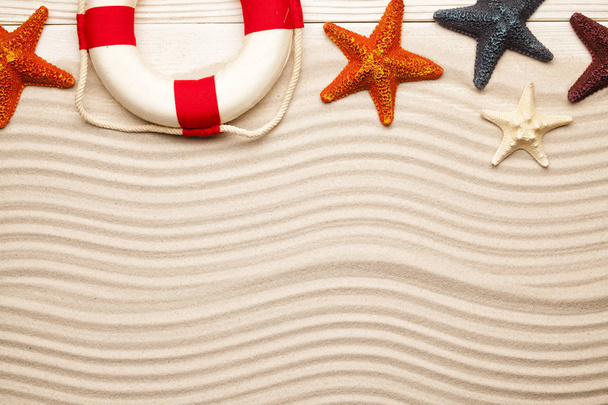 Summer background - lifebuoy and starfish on wooden plank and beach sand - Zdjęcie, obraz