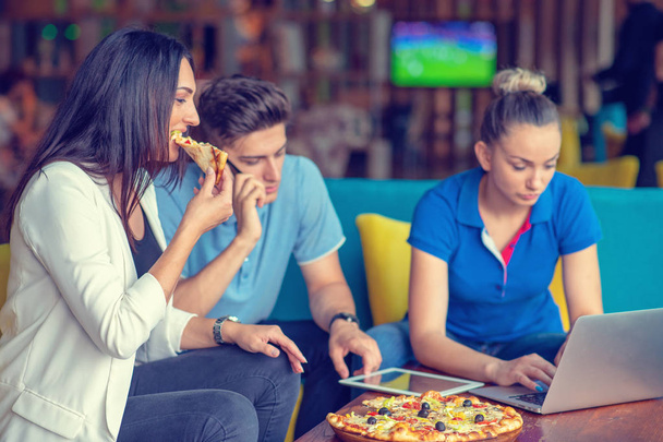 Opiskelijat ryhmä syö pizzaa tauko aikaa aikaisin seuraavan oppitunnin luokassa hauskaa ja nauttia puolueen italialainen ruoka siivu
 - Valokuva, kuva