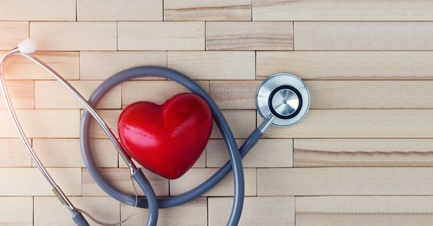 Concepto médico, corazón rojo y estetoscopio sobre fondo de madera. El equipo simbólico para el médico especializado en enfermedades cardiovasculares
. - Foto, imagen