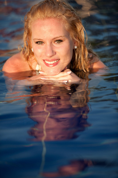 Attractive blonde girl in bikini swimwear in swimming pool on late summer afternoon - Fotografie, Obrázek