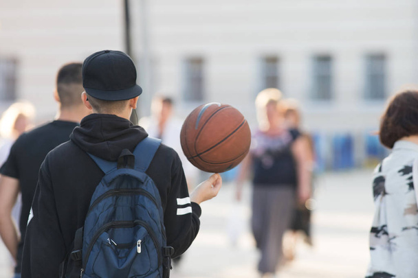 Молодий баскетболіст йде по вулиці з м'ячем
 - Фото, зображення
