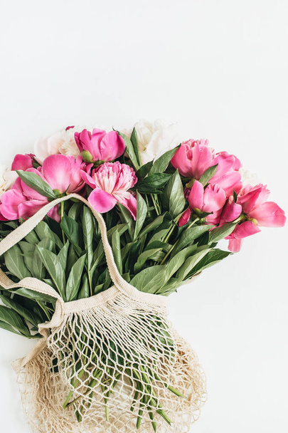 Piwonia różowy i biały bukiet kwiatów w torbie. Widok płaski świeckich, top minimalne tle kwiatów. - Zdjęcie, obraz