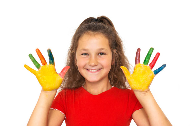 Lachende meisje toont geschilderde handen met kleurrijke verf. Kind met kleurrijke palmen lachen. Tienermeisje heeft plezier en geniet van creativiteit. Geïsoleerd op witte achtergrond. - Foto, afbeelding