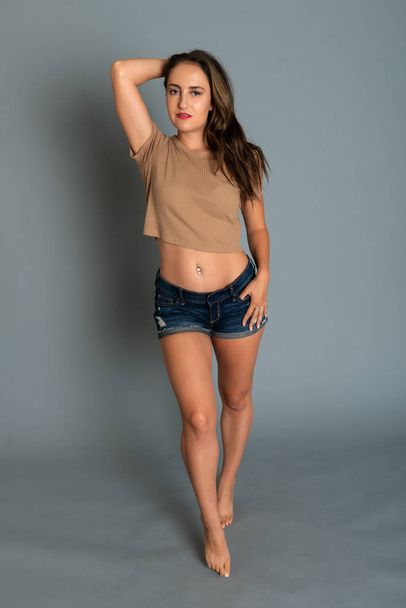 Beautiful petite brunette in a tan knit top and denim shorts - Photo, Image