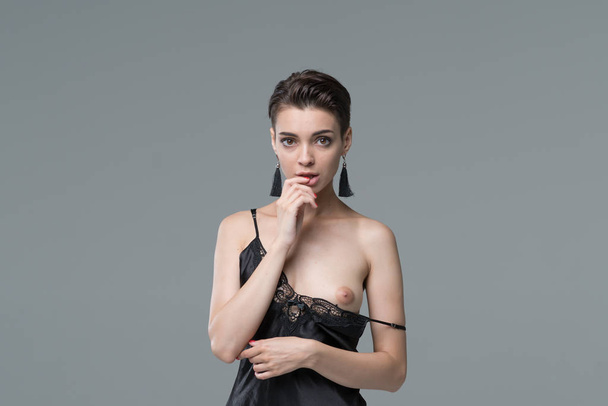 молодая красивая девушка позирует обнаженной в студии, стоя в черном белье
 - Фото, изображение