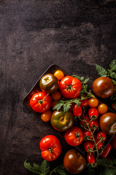 Varieties of colorful tomatos on black background - Photo, Image