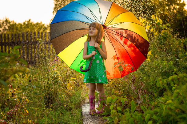 Onnellinen lapsi tyttö kävellä monivärinen sateenvarjo kesäsateessa
  - Valokuva, kuva