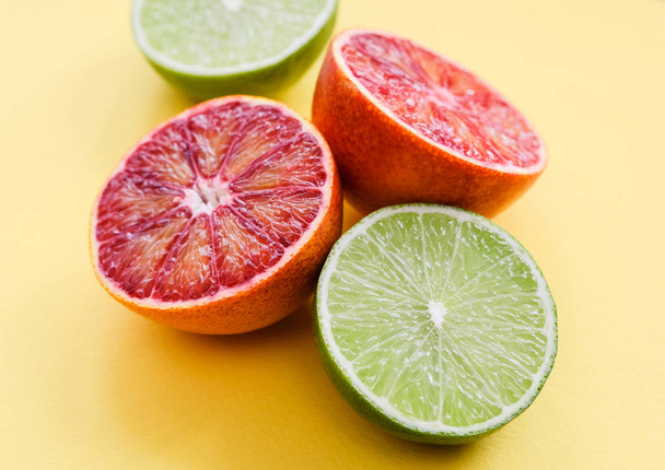 Bloody oranges and limes on yellow background - Fotoğraf, Görsel