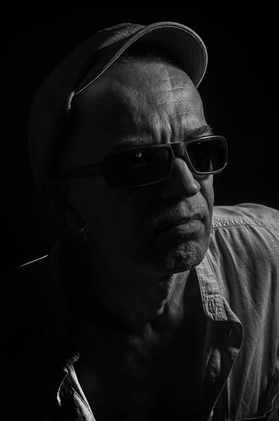 Portrait of an elderly man in a cap on a dark background . - Foto, Bild