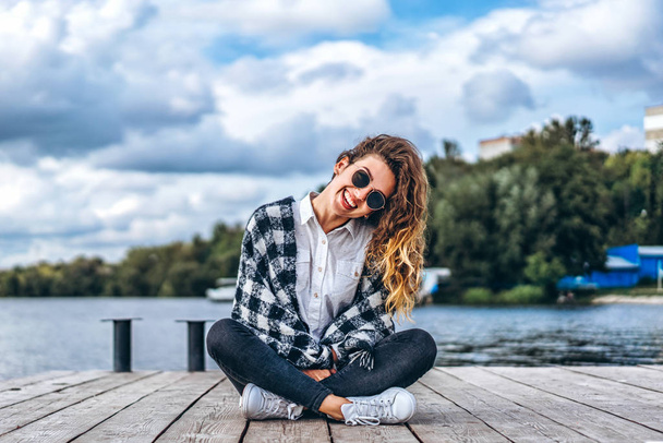 Pretty girl with curly hair relaxing near lake - Фото, зображення