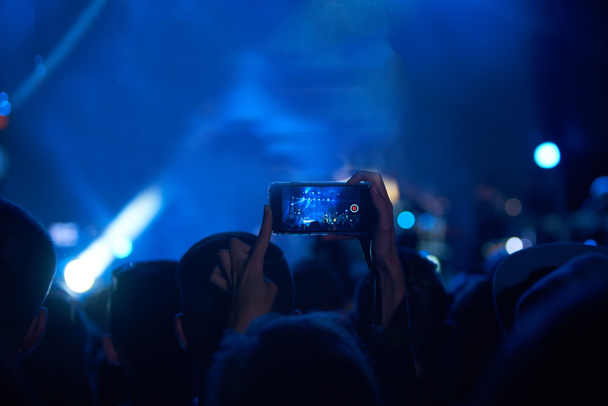 Use advanced mobile recording, fun concerts and beautiful lighting, Candid image of crowd at rock concert, Close up of recording video with smartphone, Enjoy the use of mobile photography - Photo, Image