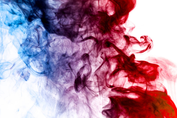 Dense multicolored smoke of   blue and red colors on a black isolated background. Background of smoke vap - Photo, Image
