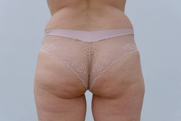 Acercamiento en las nalgas de una mujer mayor ligeramente obesa que usa bragas sexy aisladas sobre un fondo blanco
 - Foto, Imagen