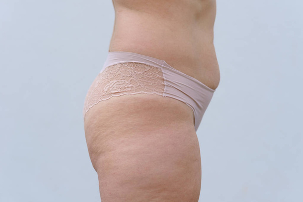 Gros plan recadré vue latérale des hanches, des cuisses et de l'abdomen d'une femme mature en culotte transparente sexy isolée sur blanc
 - Photo, image