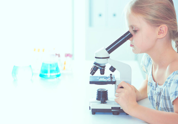 Schoolgirl looking through microscope in science class. - Fotografie, Obrázek