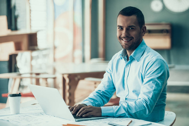Young Smiling Businessman Working in Office. Laptop in Office. Closeup of Happy Man with Bristle Sitting at Desk and Working on Laptop. Man enjoying Work. Corporate Lifestyle Concept - Foto, Imagen