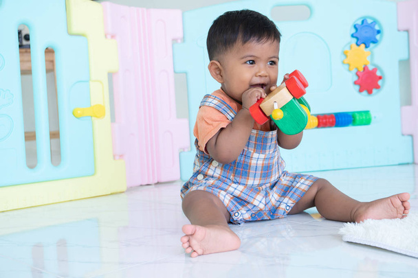 lindo poco asiático bebé chico morder madera juguete
 - Foto, Imagen