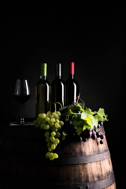 Μείγματα των μπουκαλιών ow κρασί σε βαρέλι με σταφύλι - Φωτογραφία, εικόνα