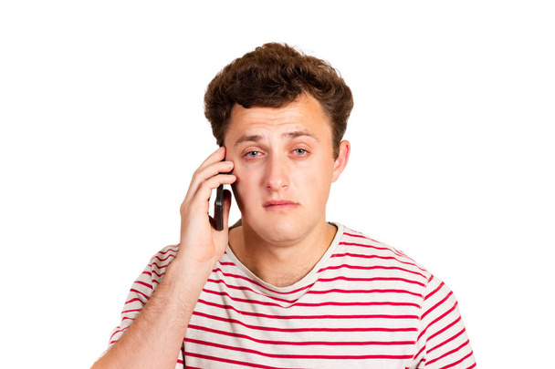Un hombre llorando lee un mensaje de texto en su teléfono. Sms con malas noticias. hombre emocional aislado sobre fondo blanco
. - Foto, imagen
