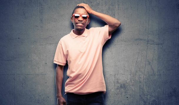 Afrikanischer schwarzer Mann mit Sonnenbrille ängstlich und nervös ausdrückende Angst und Panik Geste, überwältigt - Foto, Bild