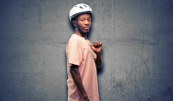 Hombre negro con casco de bicicleta orgulloso, emocionado y arrogante, señalando con cara de victoria
 - Foto, imagen