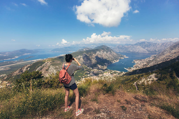 Tourist hold and look through binoculars on trip, lifestyle concept adventure, traveler with backpack on background mountain and blue sea landscape horizon. View of the Bay of Kotor from the mountains Lovcen. - Foto, Imagen