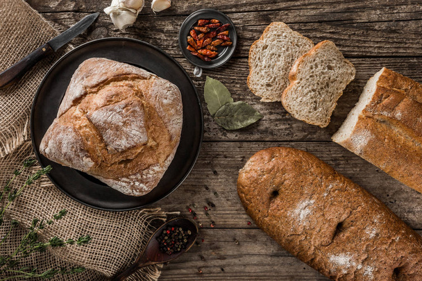 Different fresh bread and spice on rustic wooden background. Creative layout made of bread. Healthy food concept, top view, flat lay. - Photo, Image