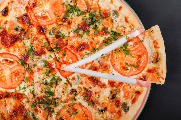 Pizza mit Huhn, Tomaten, Pilzen, Gemüse und Käse auf dunklem Holzgrund. hausgemachte Pizza. Ansicht von oben. - Foto, Bild