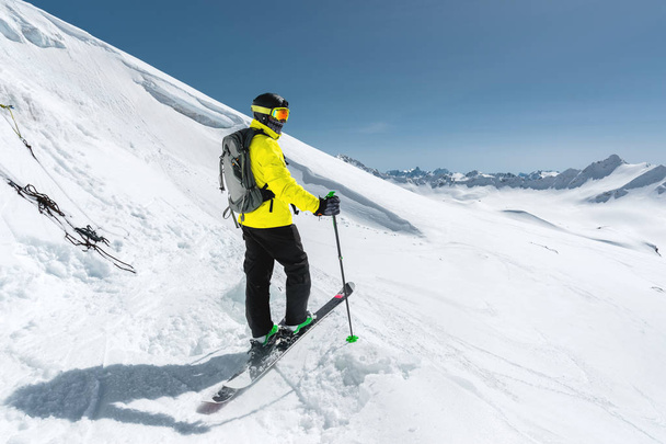 Portrait of a professional freerider skier standing on a snowy slope against the background of snow-capped mountains. The concept of winter sports - Φωτογραφία, εικόνα