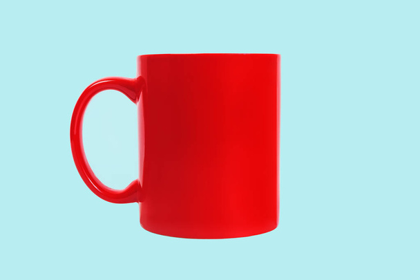Червоний керамічний кавовий кухоль ізольований на синьому фоні. Вид спереду
 - Фото, зображення
