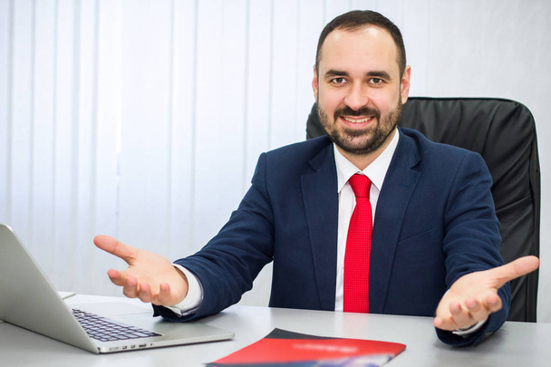 v kanceláři veselý muž v obleku s červenou kravatou zve ke spolupráci - Fotografie, Obrázek