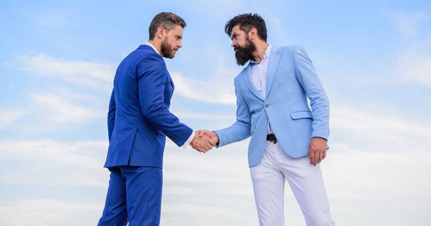 Men formal suits shaking hands blue sky background. Business deal approved accepted by both partners. Entrepreneurs shaking hands symbol successful deal. Sure sign you should trust business partner - Фото, зображення