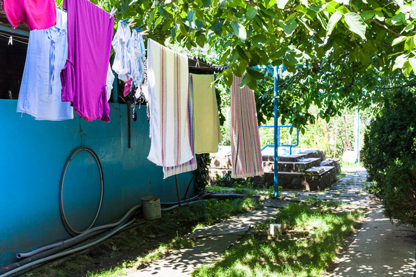 clothes drying on ropes at backyard of country house in sunny summer day in Kuban region of Russia - Photo, Image