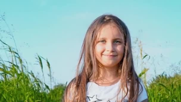 Portrét atraktivní holčička s velkýma očima zelené na pozadí přírody s vývojem vlasy - Záběry, video