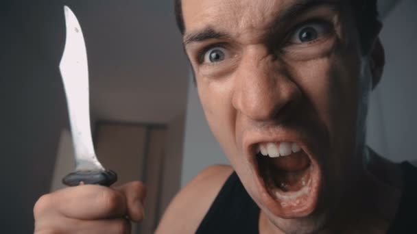 Hombre enojado gritando y amenazando con cuchillo en casa en la cocina
. - Metraje, vídeo